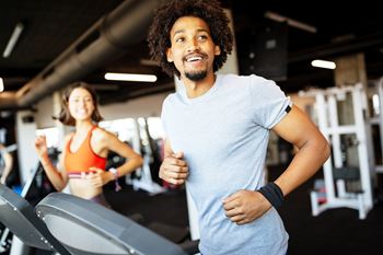 A man and a woman are working out in a gym.